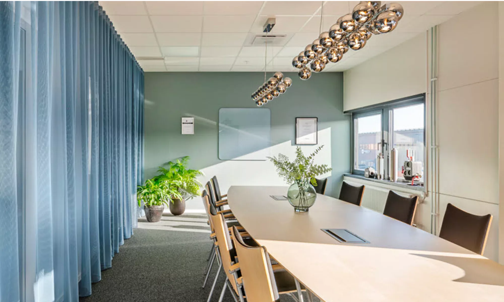 Ljust konferensrum med träbord, gröna växter och modern belysning – exempel på kontorsinredning för företag