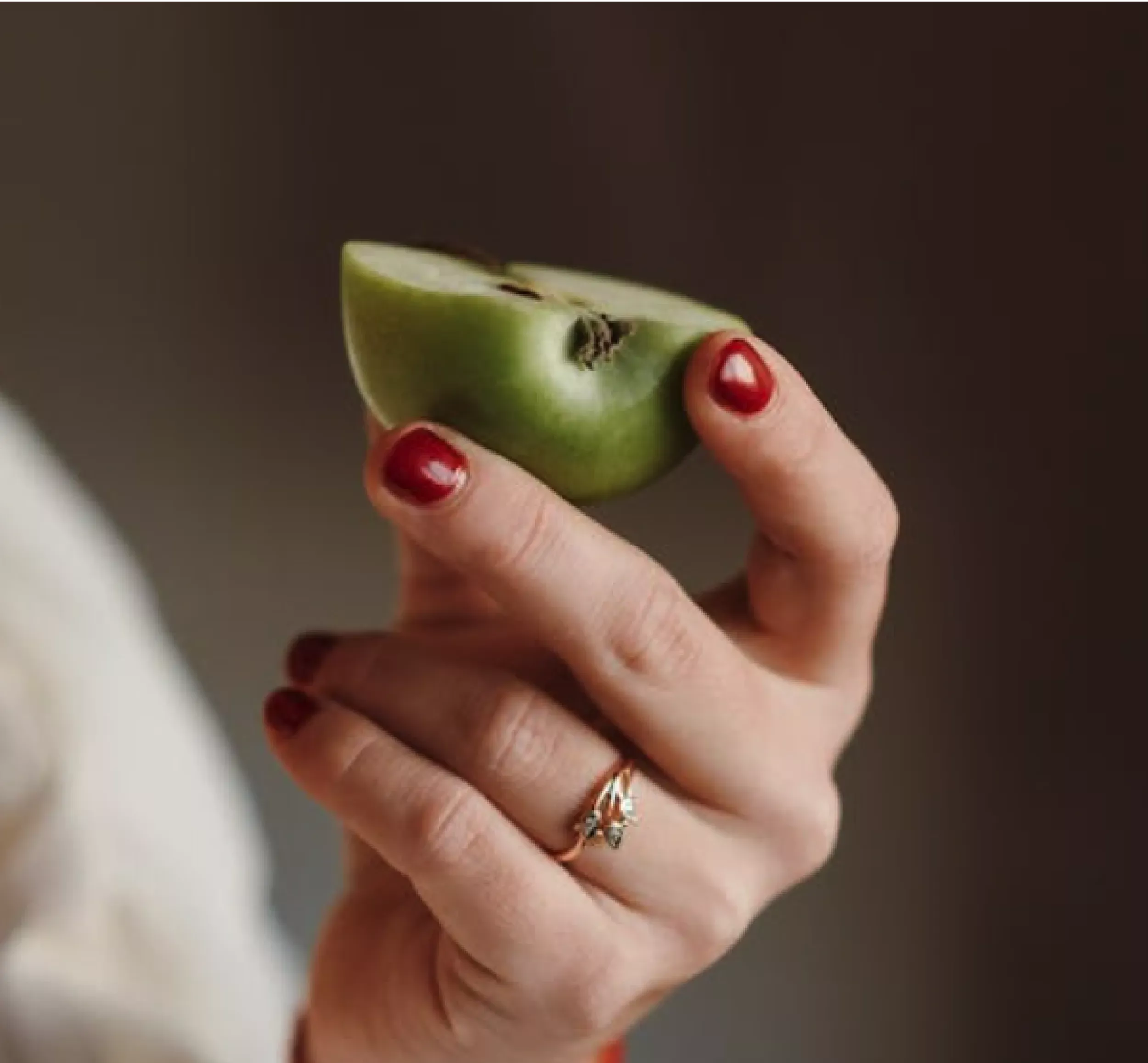 Närbild på hand med grön äppelbit, representerar friskhet och kvalitet i våra fruktkorgar för företag