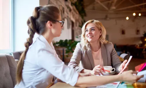 Två personer sitter vid ett bord och diskuterar inredningslösningar i en ljus och modern kontorsmiljö