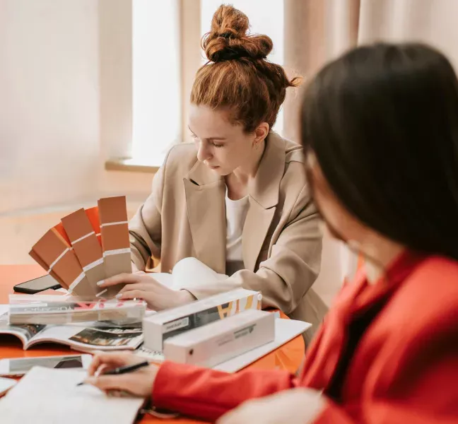 Två personer vid ett bord granskar färgprover och designmaterial