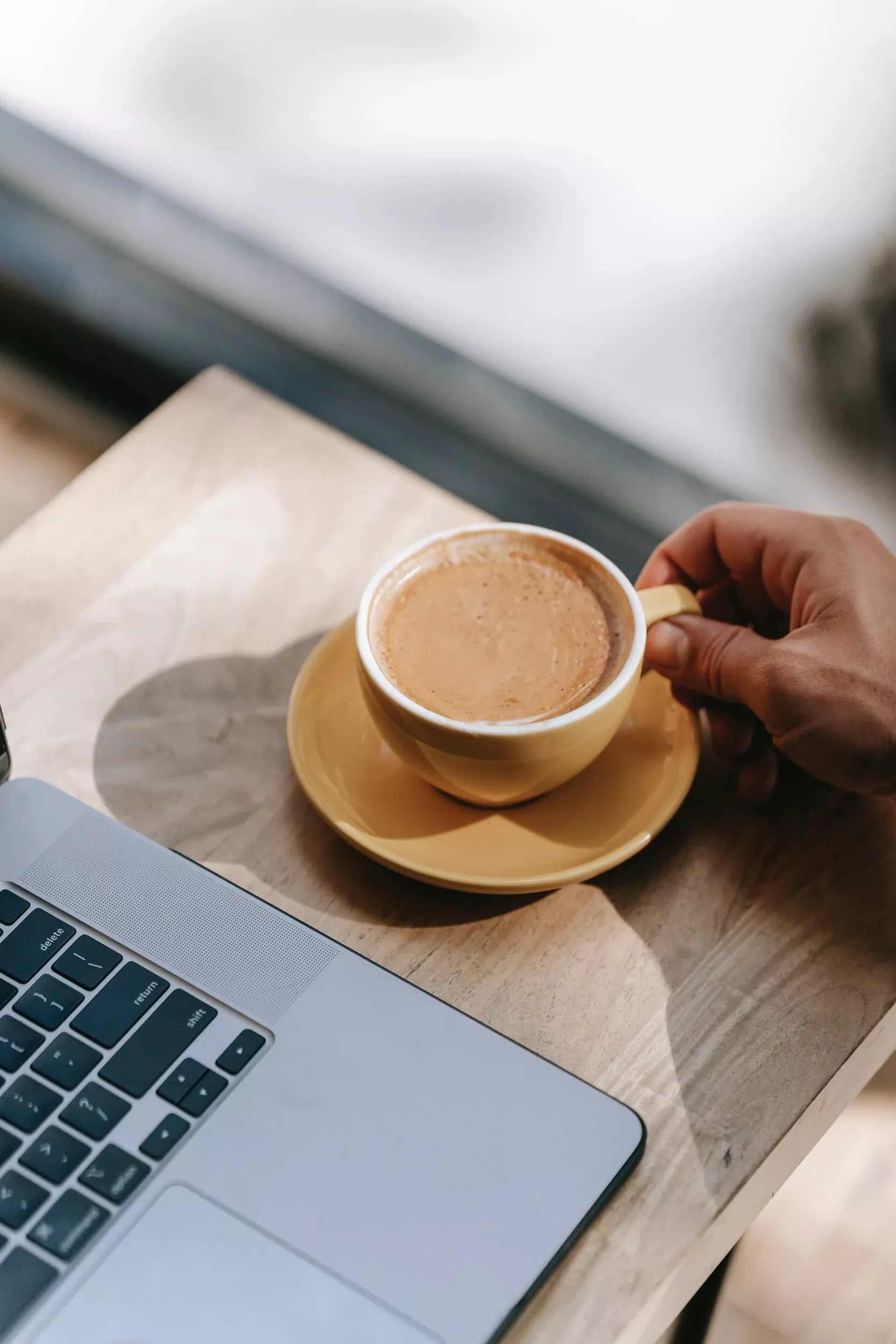 Kaffe på kontoret, kopp bredvid dator som representerar Joyweeks kaffemaskiner